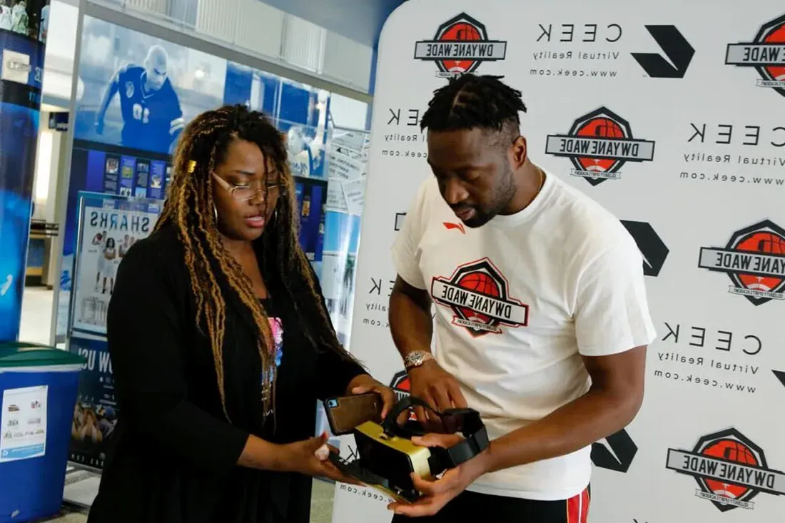 Mary Spio showing Swayne Wade a virtual reality headset.